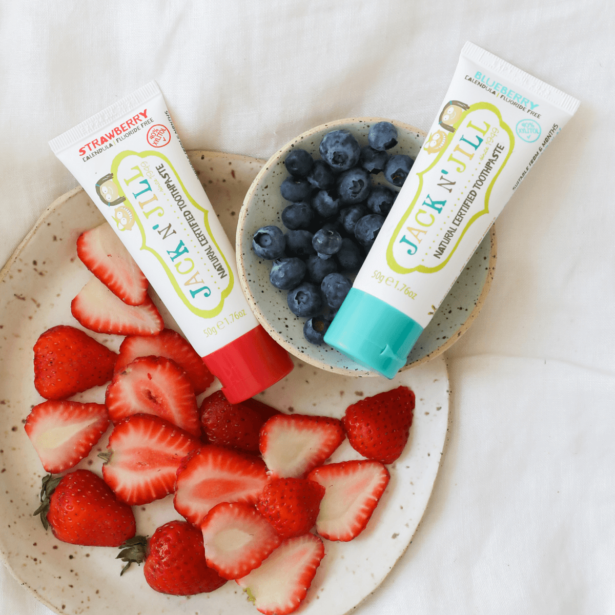 Jack N’ Jill Strawberry and Blueberry toothpaste displayed with berries