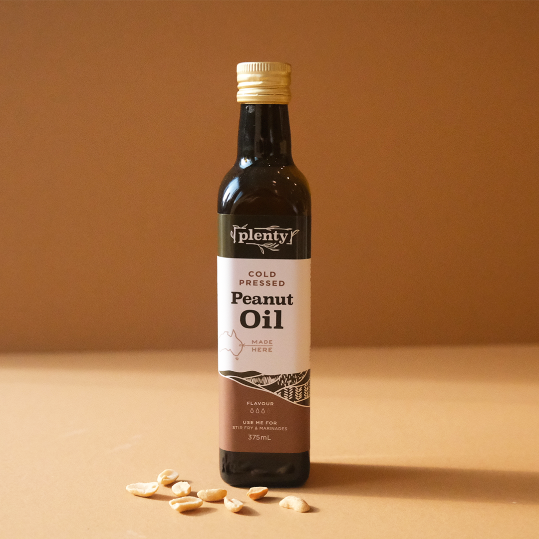 Plenty Cold Pressed Peanut Oil 375ml bottle displayed with peanuts on a warm beige background
