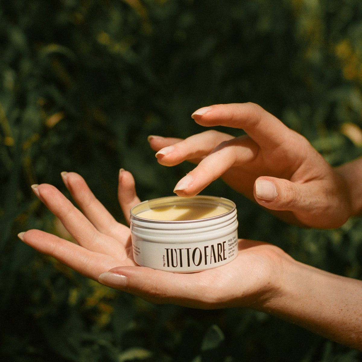 Tuttofare Holy Grail Tallow Balm 70g being scooped from open jar, outdoors